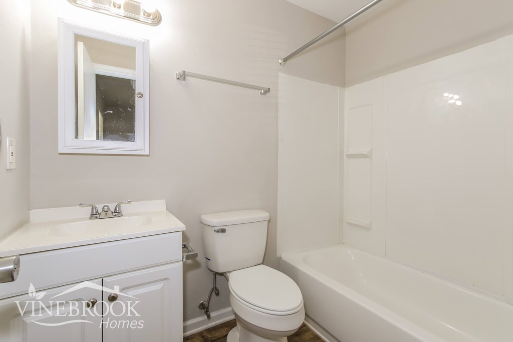 a white bathroom with a toilet and a tub and a sink